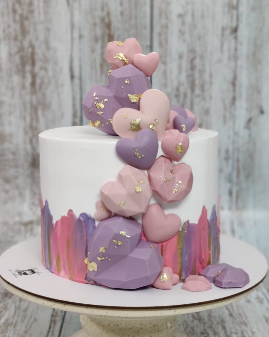 Young attractive woman holding two cakes. One pink one chocolate with chef  hat and baking utensils:: tasmeemME.com